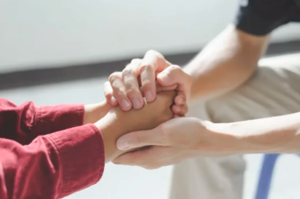 doctor holding patients hand while the patient is explaining their addiction struggles